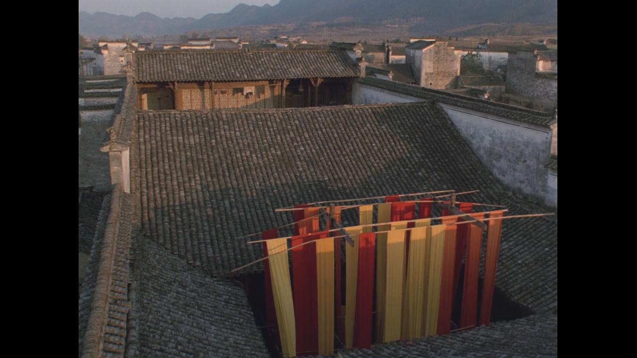 红黄两色的染布与周围灰色的建筑