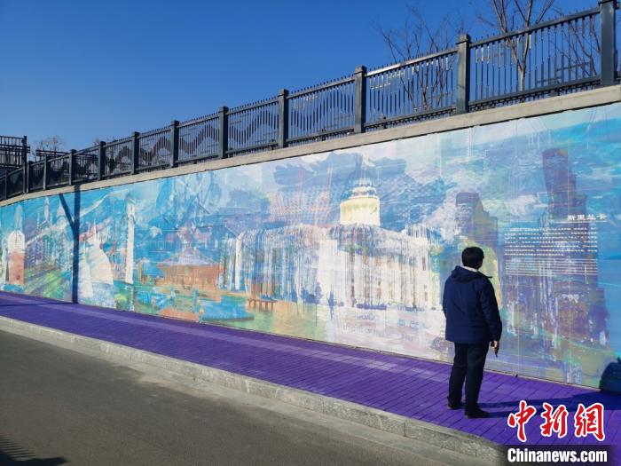 行人驻足欣赏墙上绘制的“新丝绸之路经济带”和“21世纪海上丝绸之路”沿线风景。钟升 摄