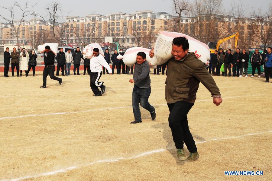 Farmers run with sacks of grain on the shoulder during a game in Yaogou Township of Sihong County in Suqian, east China's Jiangsu Province, Dec. 27, 2020. The fun games, held annually in Yaogou Township before the New Year's Day since 2018, consist of eight interesting competitions which are close to farmers' life this year. (Photo by Xu Changliang/Xinhua)