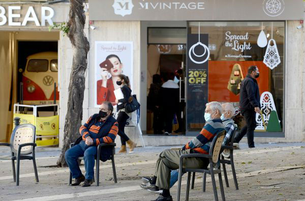 11月27日，几位老年人坐在马耳他首都瓦莱塔一家贴有打折海报的商店前。新华社发