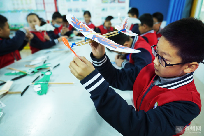12月1日,邹平市高新街道梁邹小学学生在组装航模.