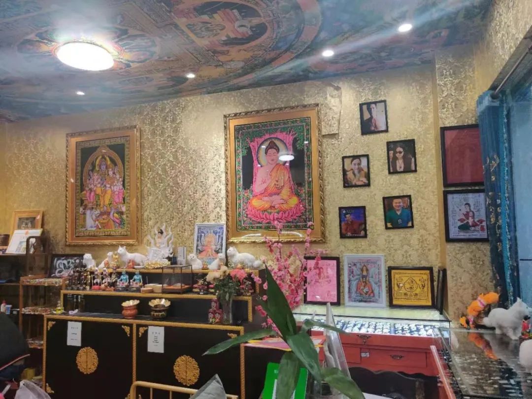 墙壁都挂满了佛像和人像,店内还摆有两处佛台,一些展示佛牌的展览柜