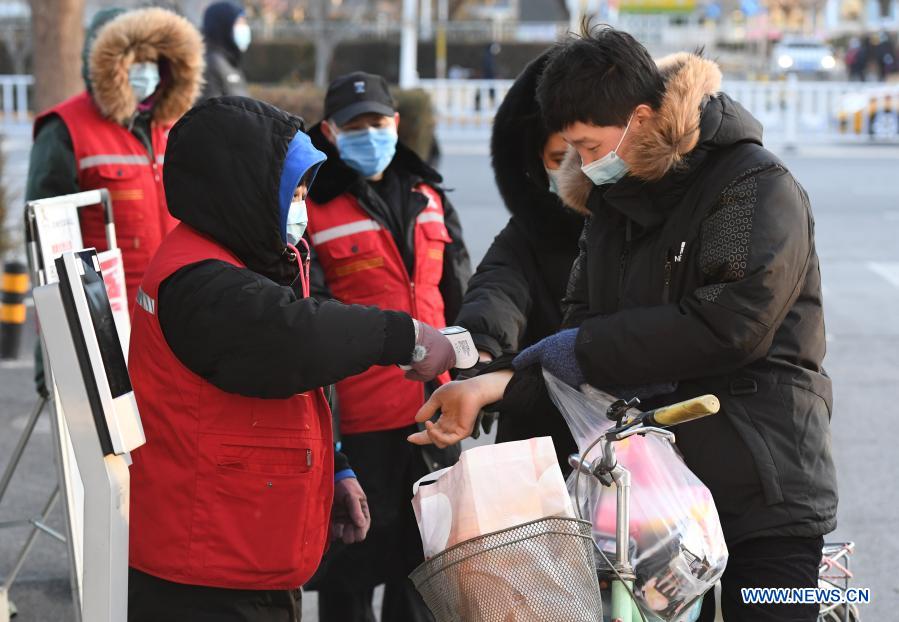 A community worker (L front) measures body temperature for a resident at the entrance of the Hongcheng Huayuan residential compound on Wangquan Street, Shunyi District, Beijing, capital of China, on Dec. 29, 2020. Beijing reported seven new locally-transmitted confirmed COVID-19 cases on Monday, according to the Beijing municipal health commission. The seven patients, who live in the Shunyi District, are all close contacts of earlier reported cases. (Xinhua/Ren Chao)