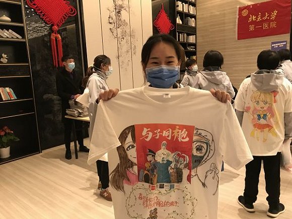 大学第一医院第三批援鄂队员崔俊举着钢花小学吴苏童小朋友涂鸦的t恤