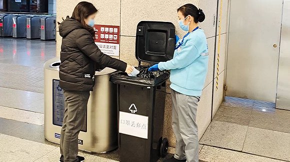 工作人员引导旅客分类丢弃口罩.