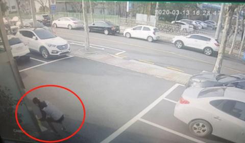 13日，一名残疾小伙在韩国釜山新湖派出所前，丢下一袋口罩。