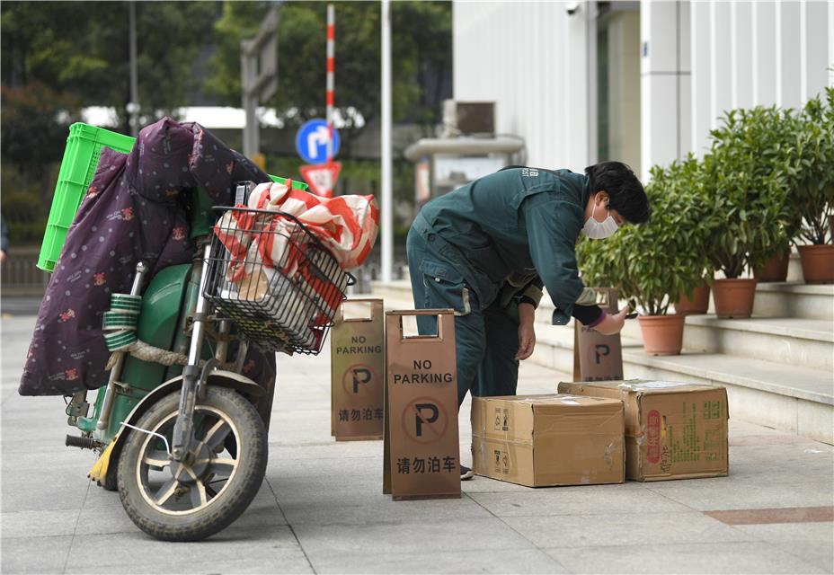  3月20日，湖北省武汉市洪山区珞喻路，中国邮政快递员在送货。
