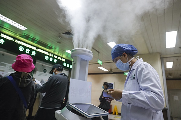  3月16日，在武汉大学人民医院门诊大厅，医务人员使用平板电脑控制智能消毒机器人。新华社 图