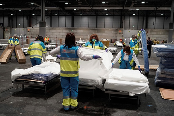 3月22日，在西班牙马德里，医务人员在马德里会展中心改造成的野战医院中准备病床。新华社 图
