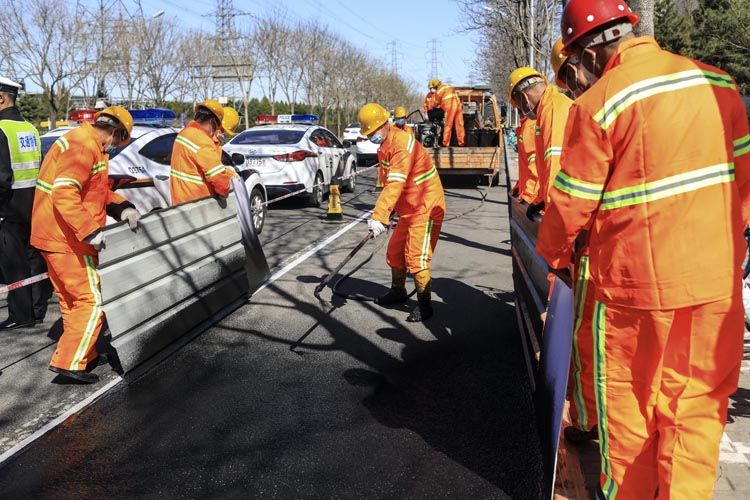 3月28日，上地西路，工人在用“雾封层”技术清除白色停车位划线。