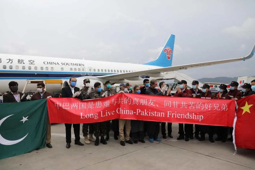 人员   与中国医疗队专家   共同拉起写有   "中巴两国是患难与共的真