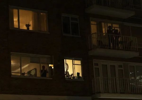 ▲3月26日，在英国伦敦，人们站在自家阳台或窗前向医护人员表达敬意。（新华社发）