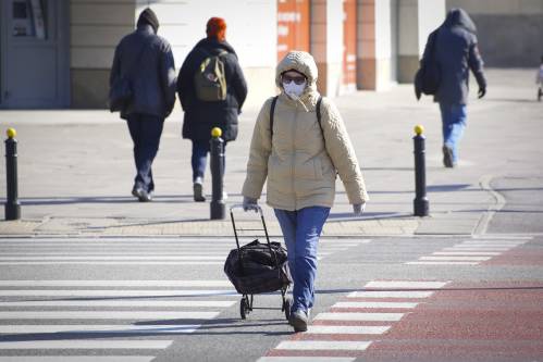 3月23日，在波兰首都华沙，一名佩戴口罩的行人过马路。新华社发