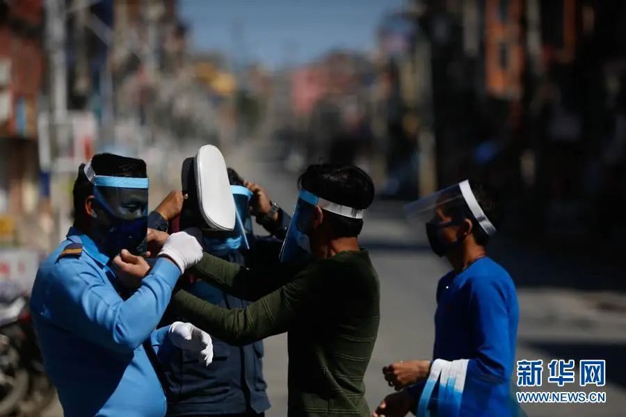  ▲3月28日，在尼泊尔加德满都，人们将自制的防护面具发给街头值勤的警察，以应对新冠肺炎疫情。新华社发（苏拉韦·什雷斯塔 摄）