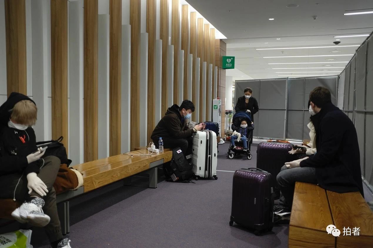 △ 当地时间3月23日晚，韩国首尔仁川国际机场，等待转运至隔离点的欧洲入境人员。