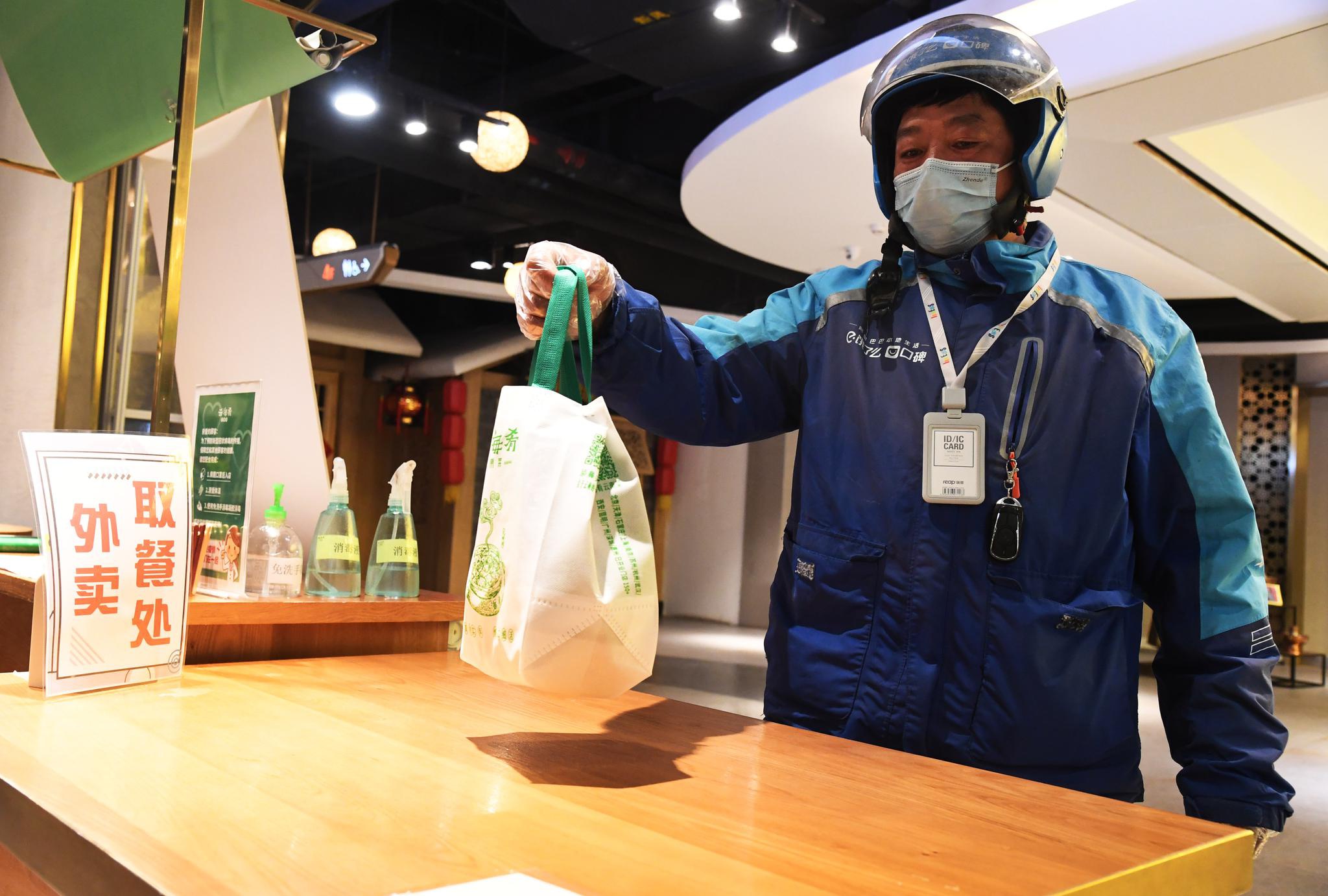 悦茂购物中心,外卖送餐员将外卖从一家云南风味餐厅的外卖取餐处取走