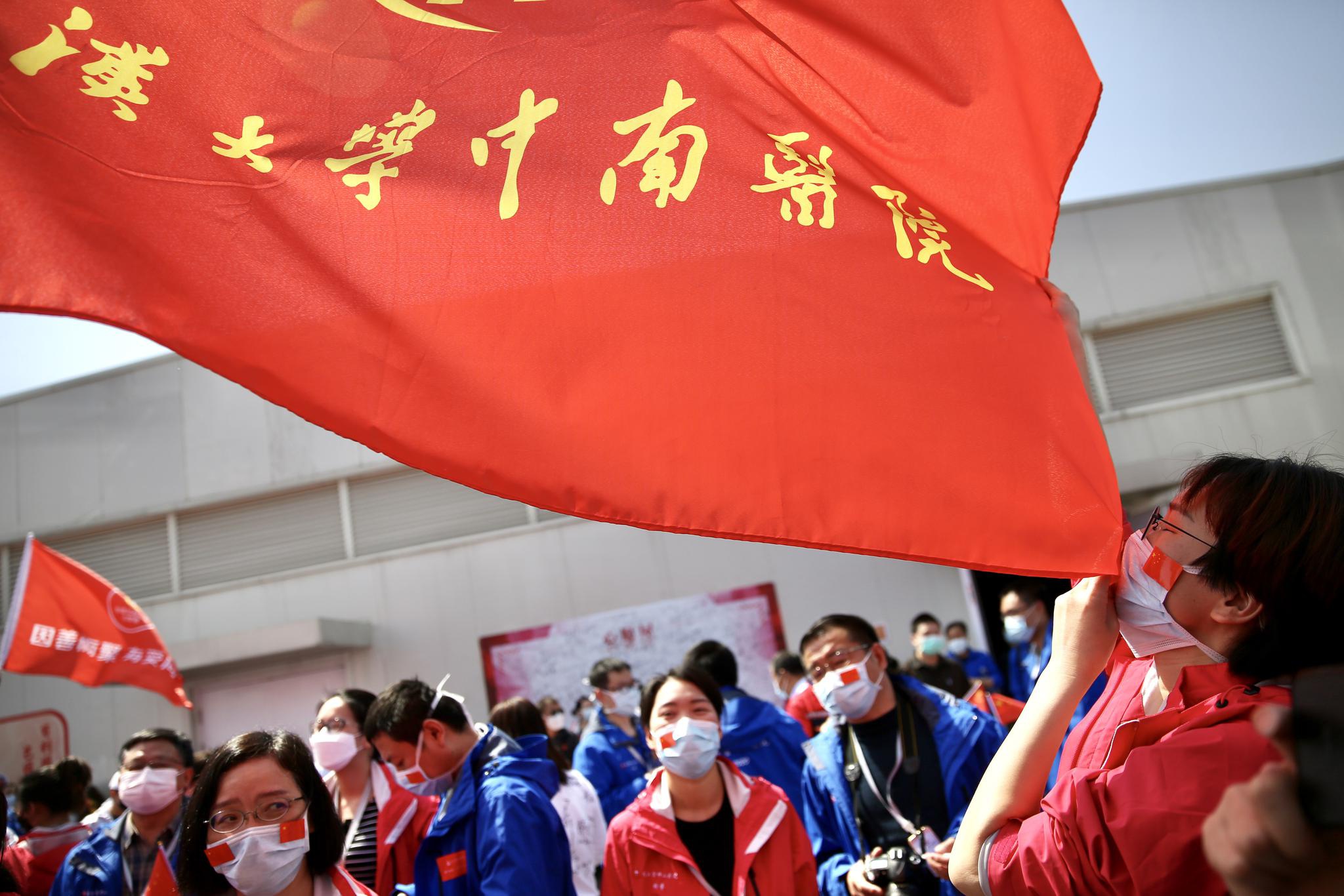 4月15日的雷神山医院休舱仪式上,一名医护人员亲吻医疗队的旗帜.