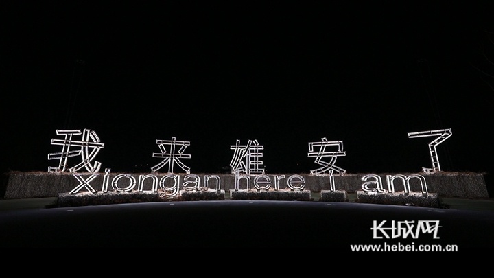 黑夜模糊的灯光中,荧光色"我来雄安了"几个字清晰醒目.
