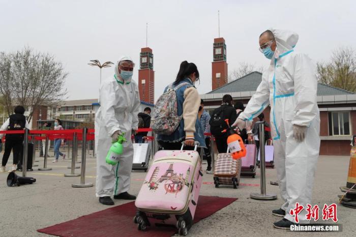  3月25日，宁夏育才中学，教职工对返校学生的行李箱进行消毒。中新社记者 于晶 摄