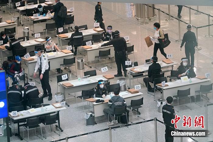 资料图:4月7日,工作人员在香港国际机场禁区为入境者办理居家检疫手续,并为入境者佩戴用于居家检疫监察的蓝牙电子手环。中新社记者 张炜 摄