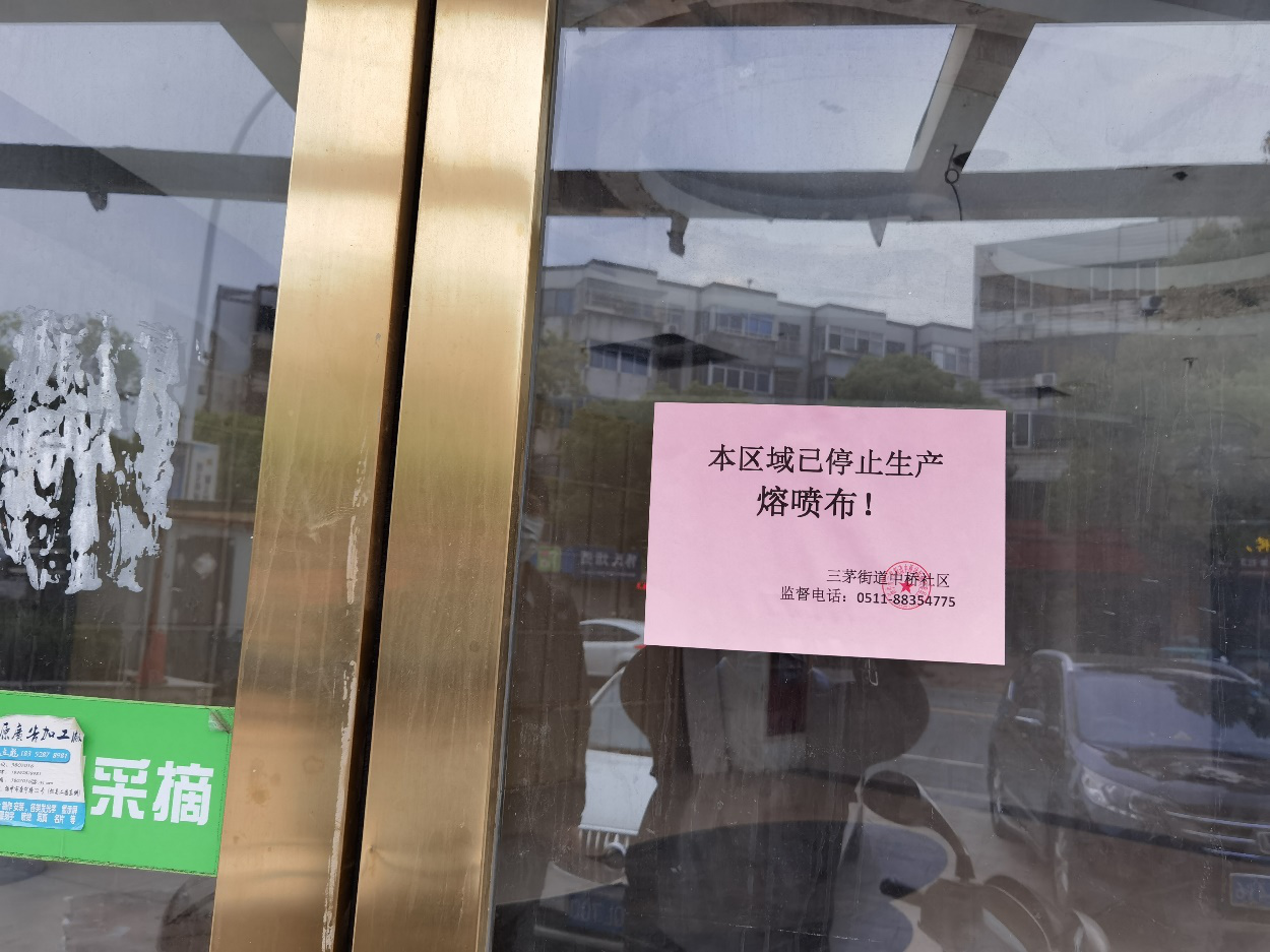 扬中市街道社区贴出关于停产熔喷布的告示。秦枭/摄影