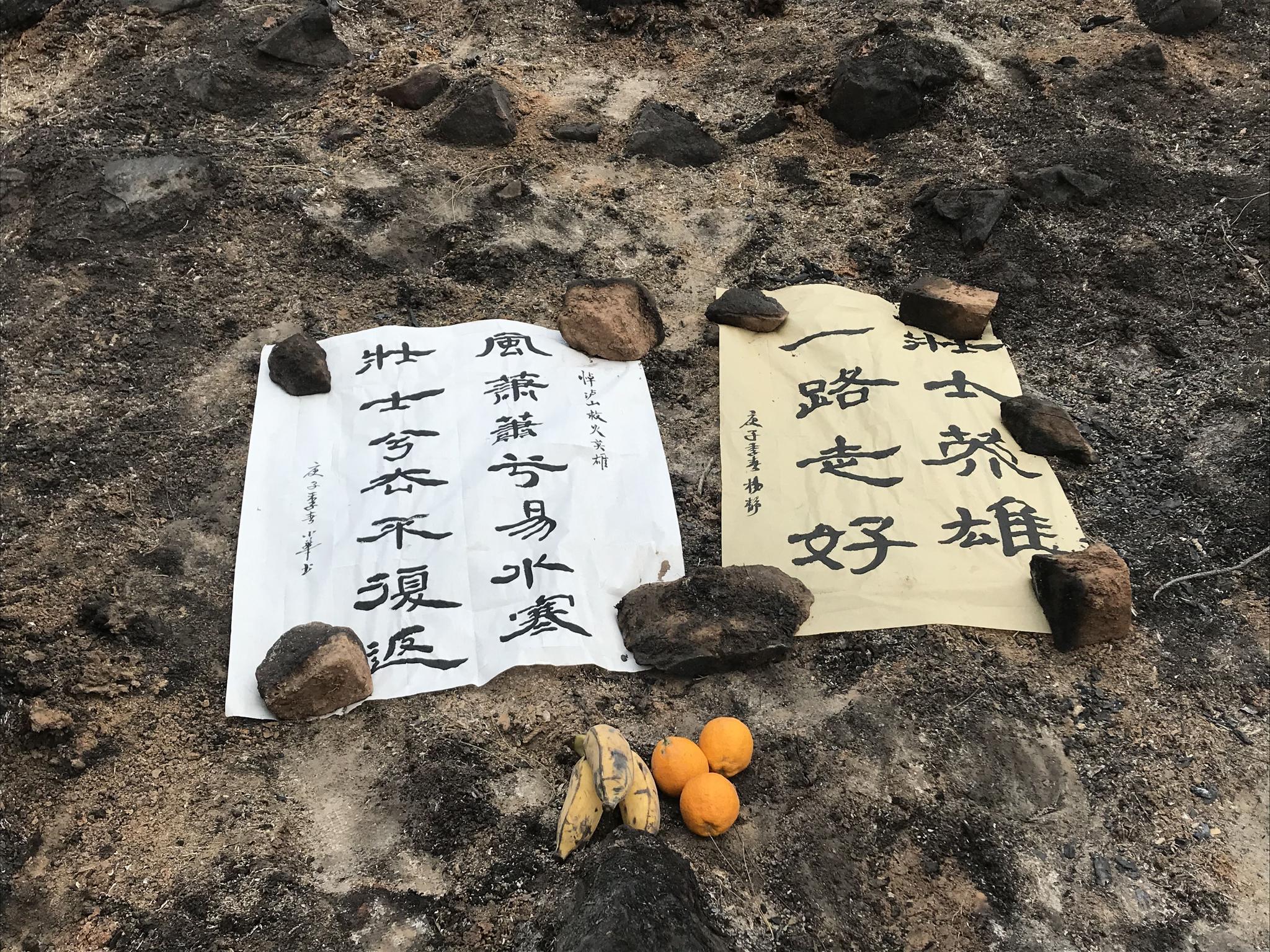 大火熏黑的山坡上，摆放着群众的悼念挽联。新京报记者 王昱倩 摄