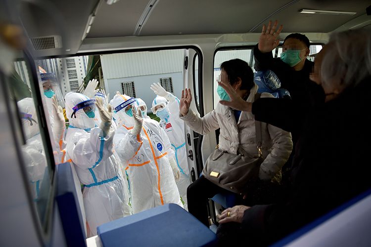  汽车开动前，出院患者与医务人员挥手道别。