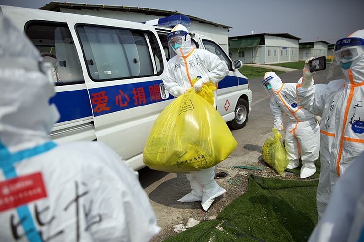  医务人员将出院患者行李搬上车。