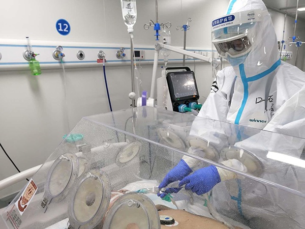 医疗队员们用自己发明的“小舱式多功能操作防护罩”为患者吸痰。
