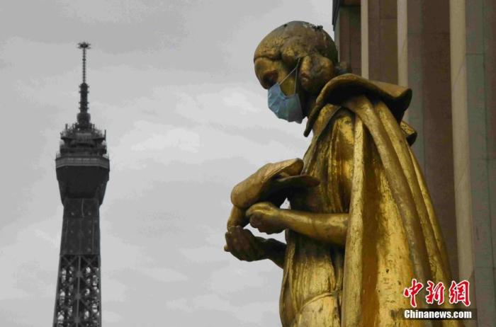 法国将于5月11日起逐步“解封”,为了提醒民众“解封”后注意防护,巴黎著名景点夏洛宫外的金色雕塑被戴上了口罩。中新社记者 李洋 摄