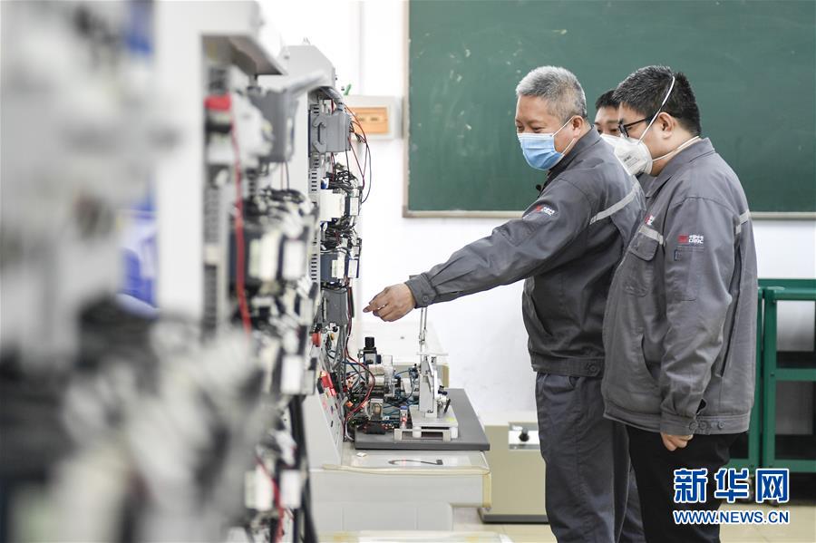 中车长春轨道客车股份有限公司首席操作师罗昭强（左一）指导工人进行高速车辆调试实训系统操作训练（4月26日摄）。新华社记者许畅&nbsp;摄