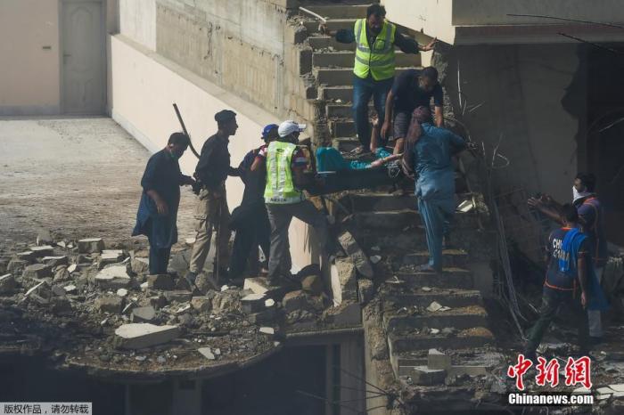 当地时间5月22日，巴基斯坦卡拉奇，志愿者在飞机失事现场将一名伤者抬出废墟。