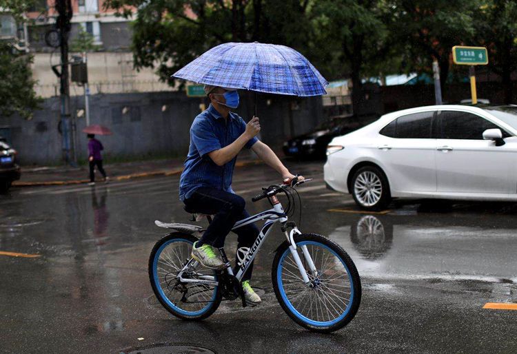  海淀区吴家场路，一名男子骑行在雨中。