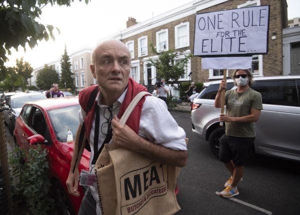 英国首相高级顾问卡明斯当地时间25日回家时，一名抗议者高举标语对他违反居家令表达不满。（欧洲新闻图片社）