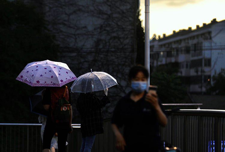 中关村东路过街天桥上,市民驻足拍摄雨景。