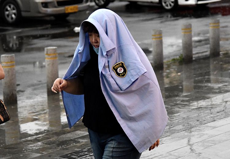 广渠路,公交乘务员把外套蒙在头上挡雨。