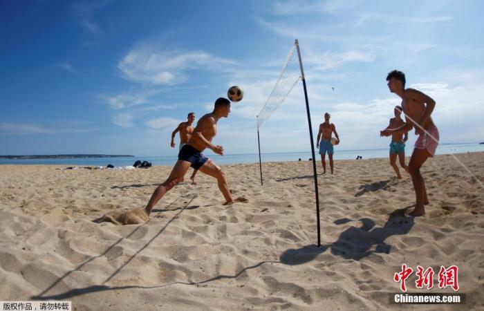 当地时间5月25日，民众在西班牙大加那利岛重新开放的海滩上玩乐休闲。据报道，随着疫情缓解，西班牙逐步放宽限制措施，一些省份放宽了解封第二阶段的一些限制。图为民众在沙滩上玩网式足球。