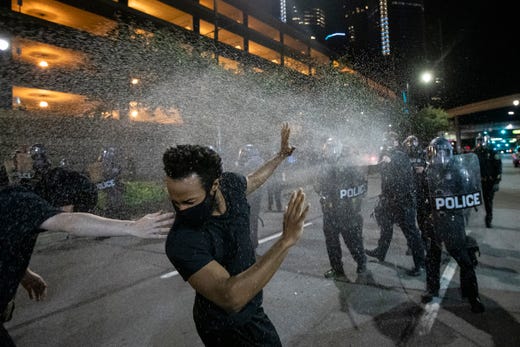  身穿防暴装备的底特律警察向抗议者喷洒胡椒喷雾  图源：底特律自由新闻报
