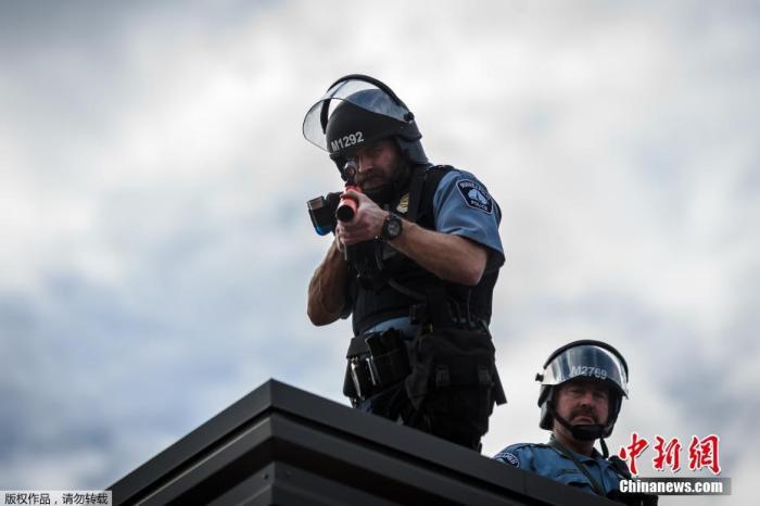 当地时间5月27日，美国明尼苏达州明尼阿波利斯市第3警察局的房顶上，两名警察手持射弹发射器瞄准示威人群。