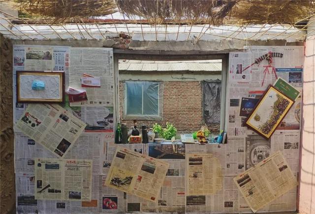 看这报纸墙和茅草房,像极作秀