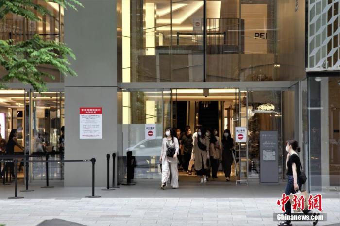 当地时间6月6日,日本东京民众戴口罩走出商场。中新社记者 吕少威 摄