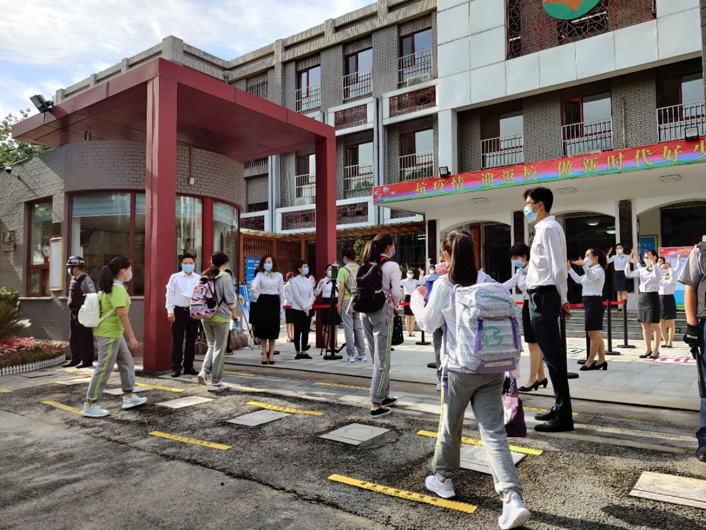 北京光明小学的学生走进校门，老师们以《你笑起来真好看》手语舞欢迎学生归来。 澎湃新闻见习记者 程婷 图