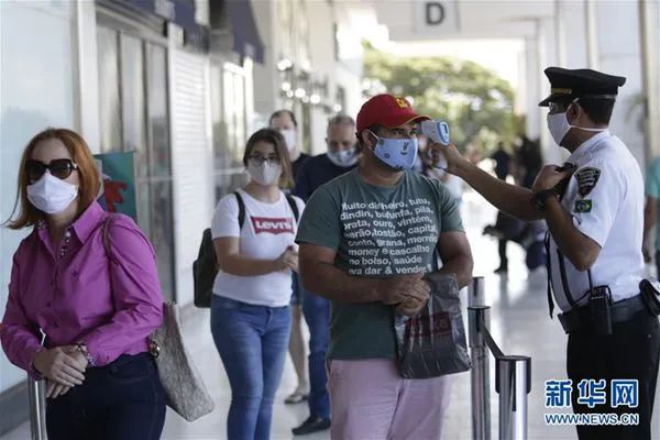  5月27日，在巴西首都巴西利亚，顾客在恢复营业的商场外检测体温。新华社发（卢西奥·塔沃拉 摄）