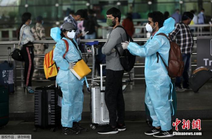  5月25日，在印度孟买希拉吉国际机场，旅客们穿戴着防护服和面罩出行。 印度政府允许国内航线自5月25日起恢复。