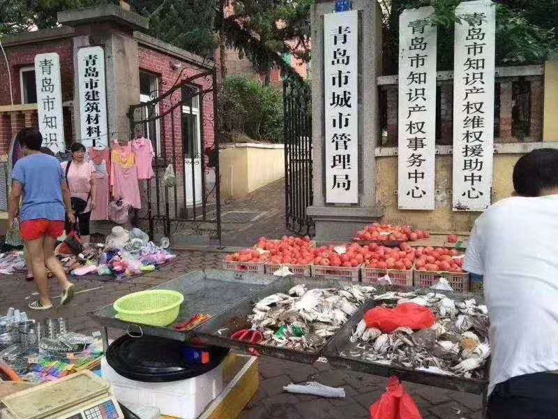 网传商贩将摊位摆放至青岛市城市管理局门前,青岛回应系旧图。图片来源于网络