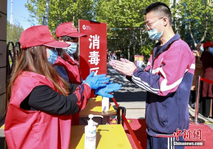 资料图：4月23日，在河北省廊坊市大厂回族自治县回民中学，志愿者指导返校学生进行消毒。 中新社记者 宋敏涛 摄