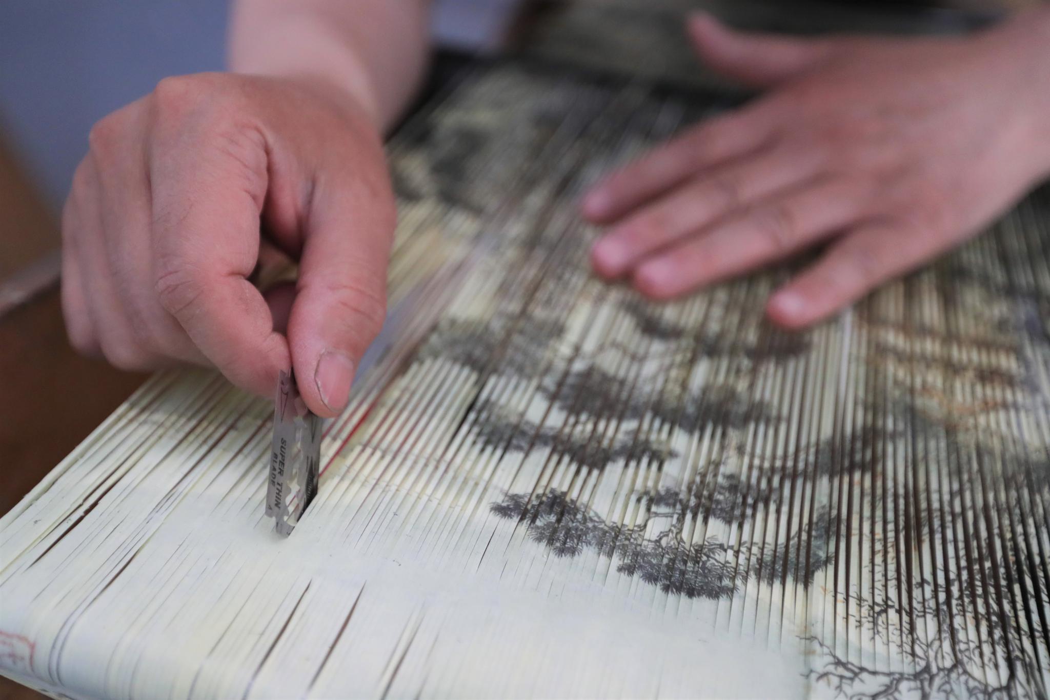 7月8日,在庄浪县泥金纸织画传习所,魏巍在裁切国画,制作泥金纸织画