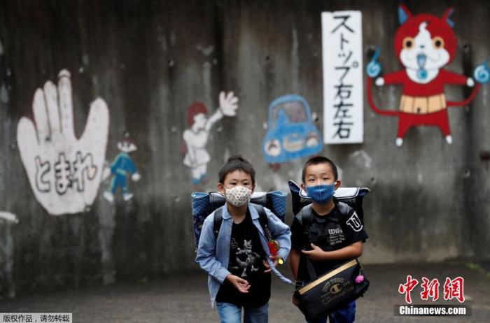当地时间7月16日,日本东京,孩子们戴着口罩结伴上学。
