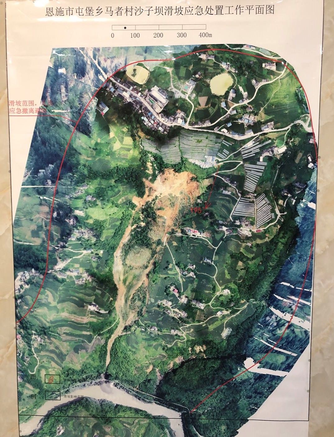 7月23日,挂在村委会办公室的滑坡航拍图,危险区域用红线标出。新京报记者 向凯 摄