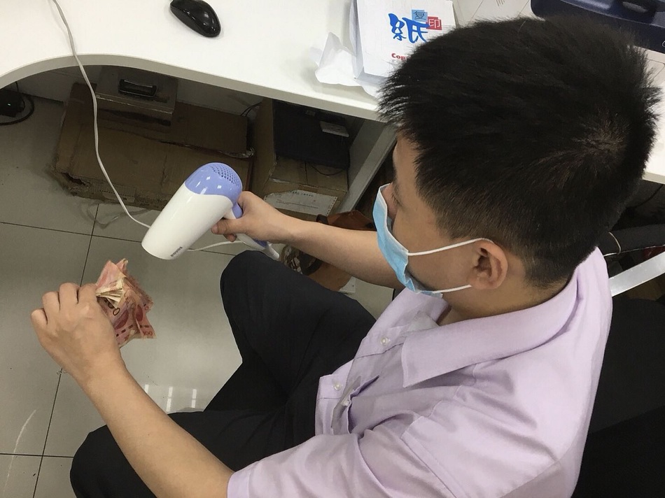 做事人员借助吹风机对“霉”币进走干燥处理。